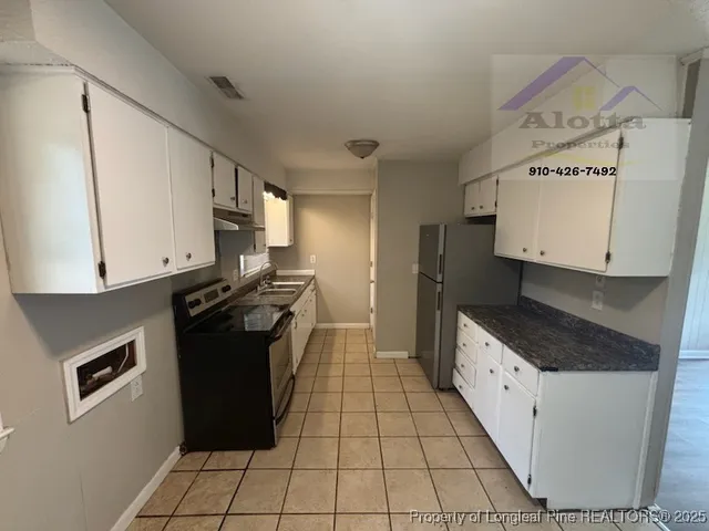 a kitchen with granite countertop a stove a sink and a refrigerator
