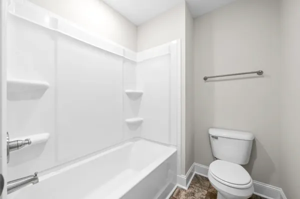 a white toilet sitting next to a bath tub
