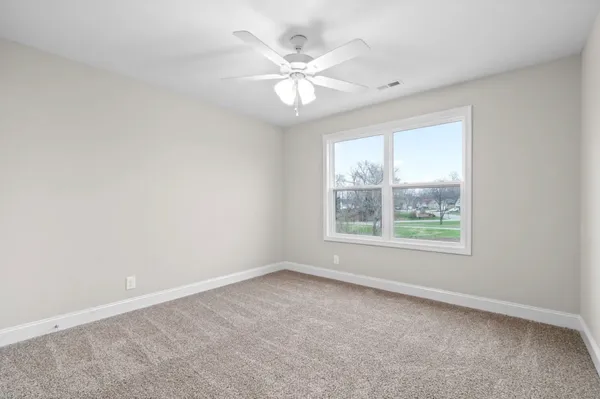 an empty room with windows and chandelier fan