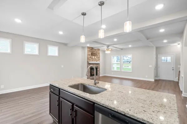 a kitchen with stainless steel appliances granite countertop a sink a window and wooden floor