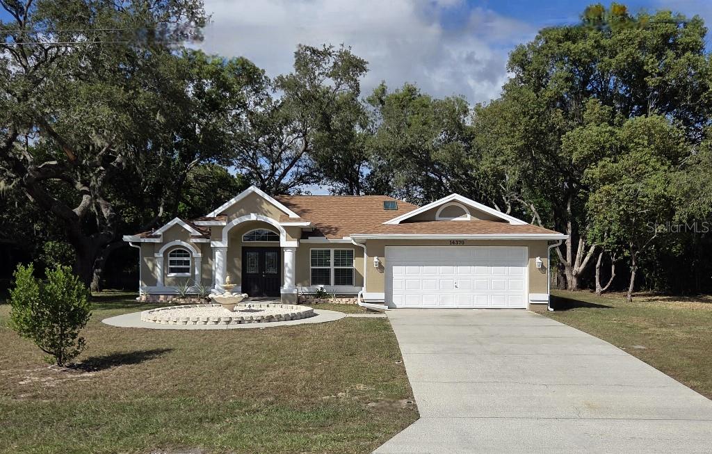 Undisclosed Address Spring Hill, FL 34609 - Photo 1 of 50 a front view of a house with a yard and large trees