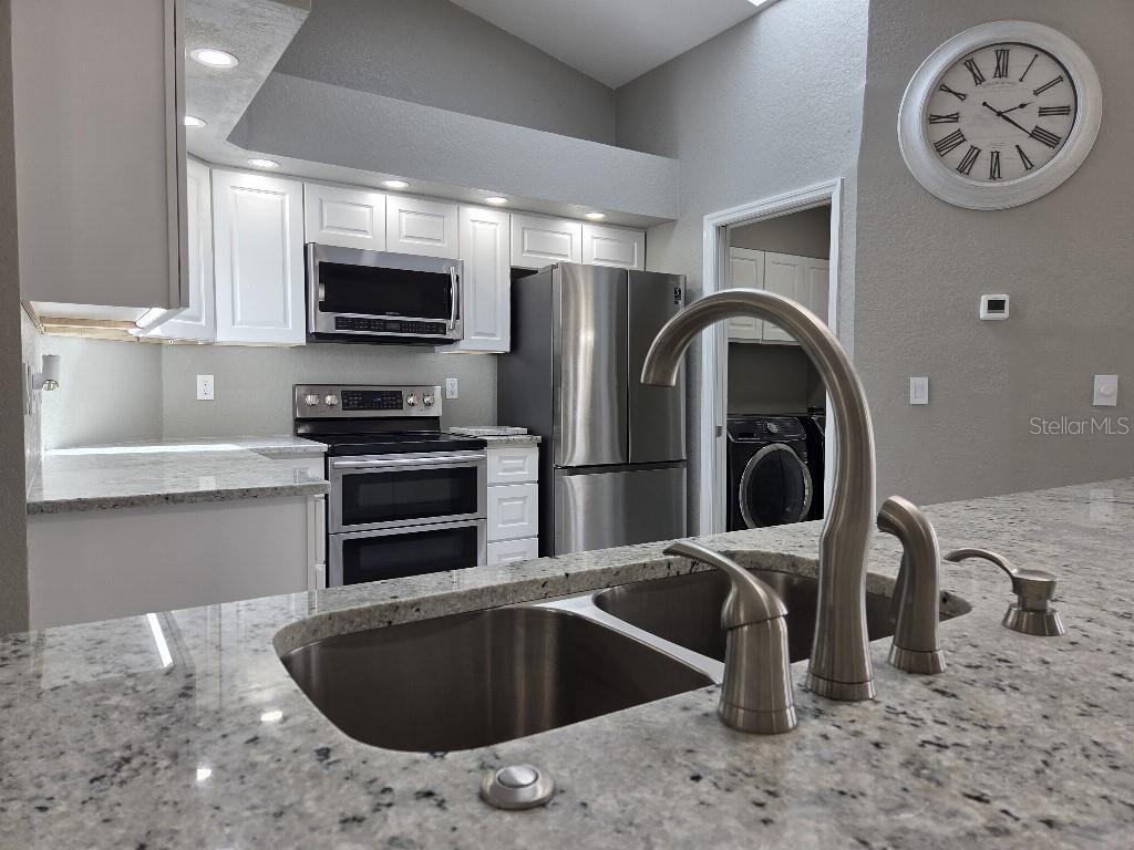 Undisclosed Address Spring Hill, FL 34609 - Photo 7 of 50 a kitchen with stainless steel appliances granite countertop a sink and a stove top oven with wooden floor