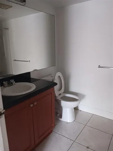 a bathroom with a granite countertop sink and a toilet