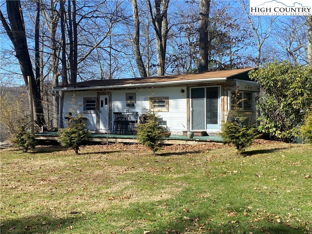 a view of house with yard outdoor seating and covered with trees