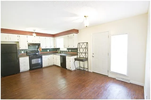 a kitchen with a refrigerator and white cabinets