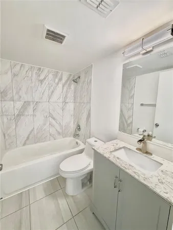 a bathroom with a granite countertop sink a toilet a mirror and bathtub