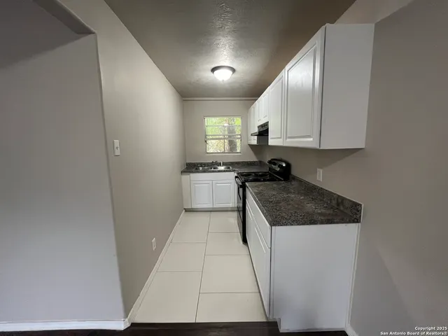 a kitchen with granite countertop white cabinets and stainless steel appliances