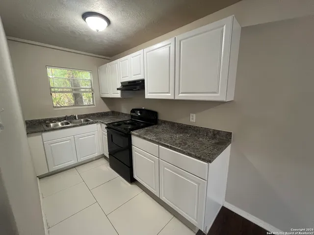 a kitchen with cabinets appliances a sink and a window
