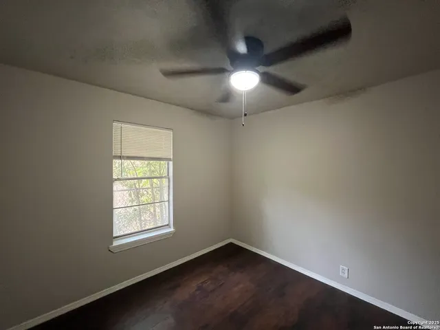 an empty room with a window and a fan