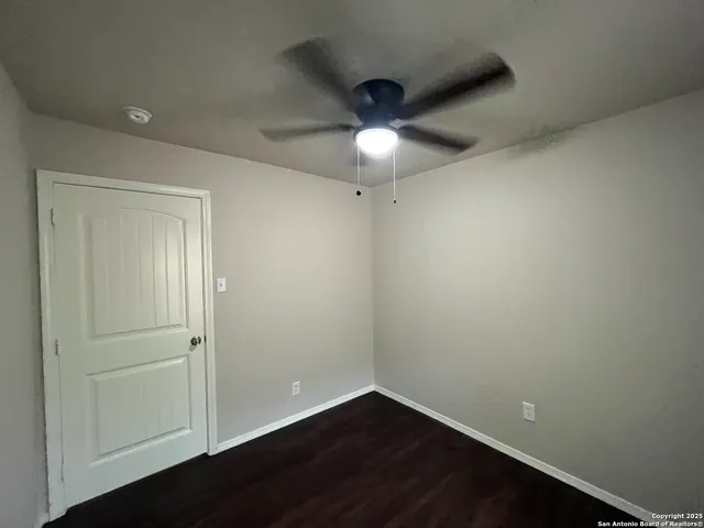 an empty room with a ceiling fan and wooden floor