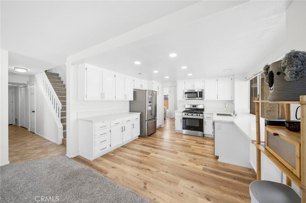 9253 Sunridge Drive Riverside, CA 92508 - Photo 18 of 57 a large kitchen with cabinets wooden floor and stainless steel appliances