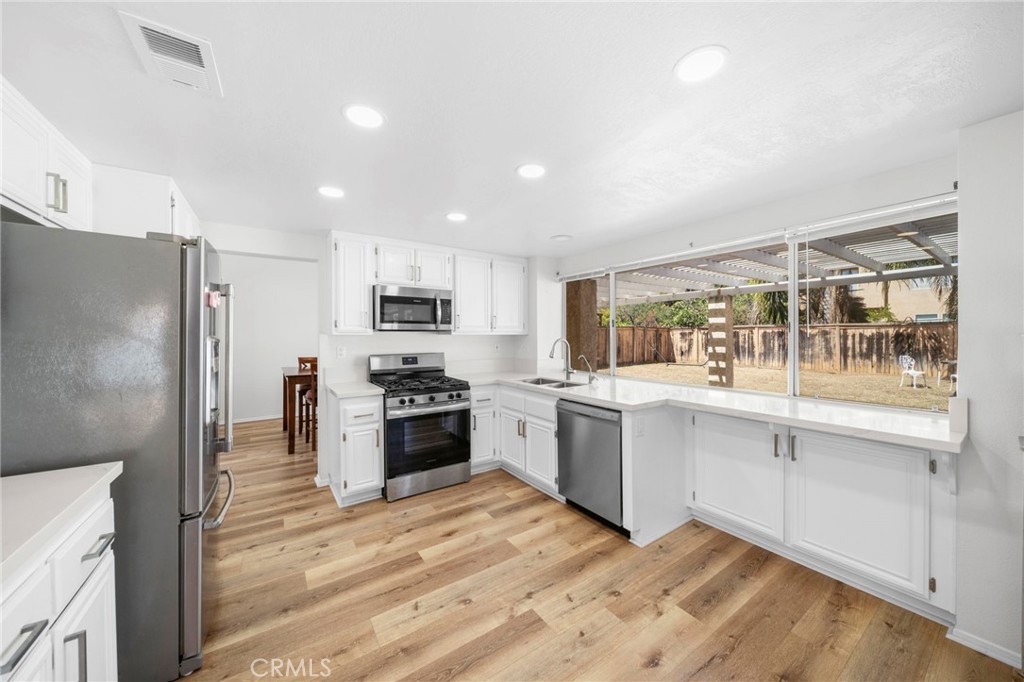 9253 Sunridge Drive Riverside, CA 92508 - Photo 19 of 57 a large kitchen with cabinets wooden floor and stainless steel appliances