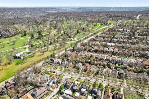 an aerial view of residential houses with outdoor space and trees