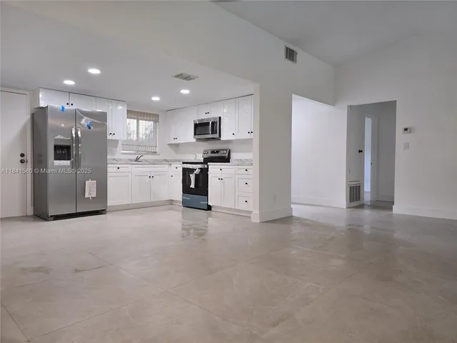 a large kitchen with stainless steel appliances granite countertop a refrigerator and a stove top oven