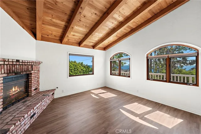 a view of an empty room with wooden floor fireplace and a window