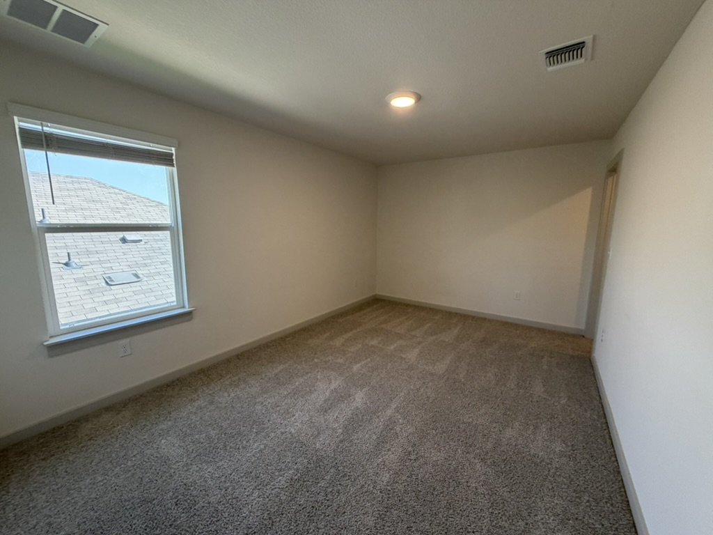 10708 Gonzales Ranger Pass Austin, TX 78754 - Photo 12 of 40 A well-lit bedroom with ample space, featuring soft carpeting and natural light from a generous window.