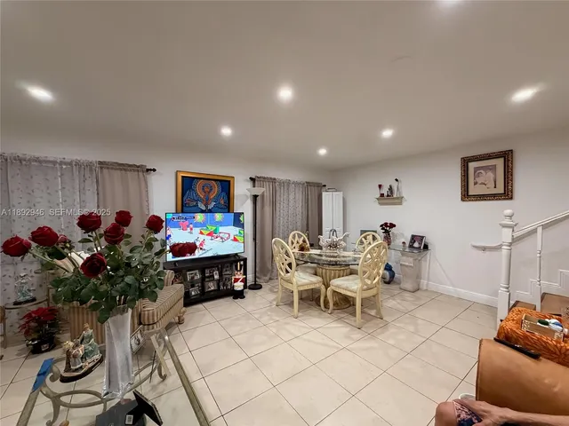 a living room with furniture a flowers and a flat screen tv