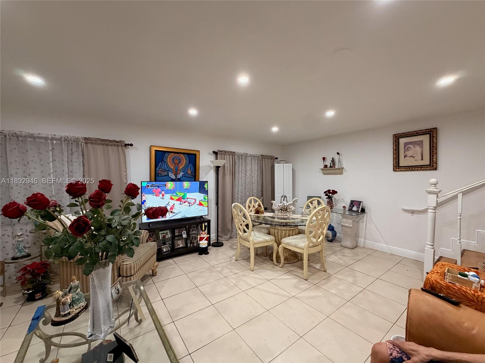 1350 West 53rd Street, Unit 24 Hialeah, FL 33012 - Photo 4 of 32 a living room with furniture a flowers and a flat screen tv