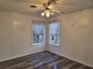 a view of an empty room with window and wooden floor
