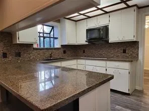 a kitchen with granite countertop a sink a stove and microwave