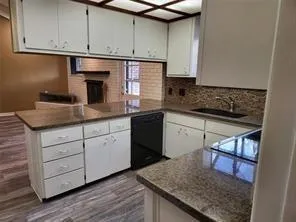 a kitchen with a sink dishwasher a stove and white cabinets with wooden floor