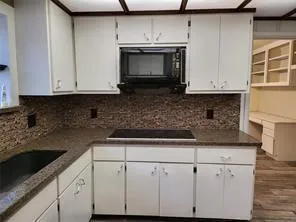 a kitchen with granite countertop white cabinets and a stove