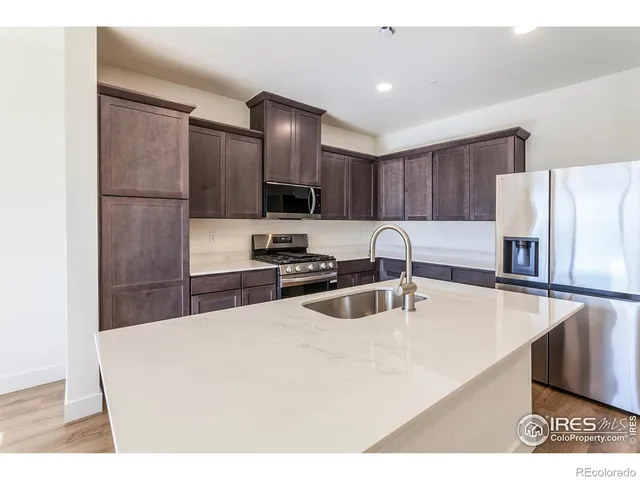a kitchen with stainless steel appliances a sink a stove a refrigerator with white cabinets