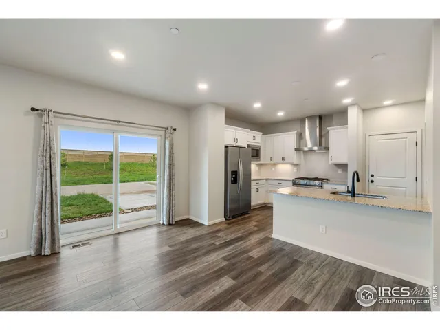 a open kitchen with stainless steel appliances granite countertop a refrigerator a sink a stove and a wooden floors