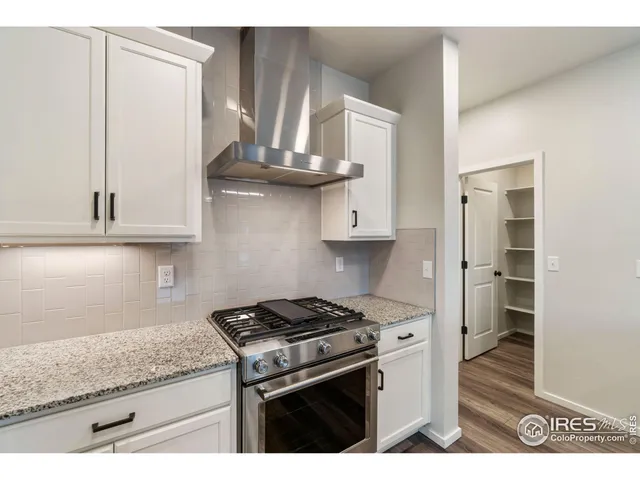 a kitchen with stainless steel appliances granite countertop a stove a refrigerator and a white cabinets