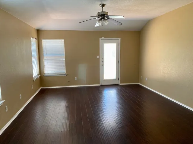 a view of an empty room with wooden floor and a window