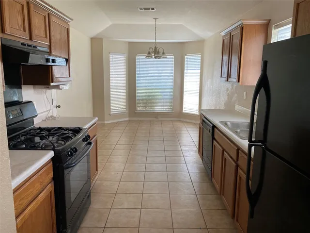 a kitchen with granite countertop a refrigerator stove and sink