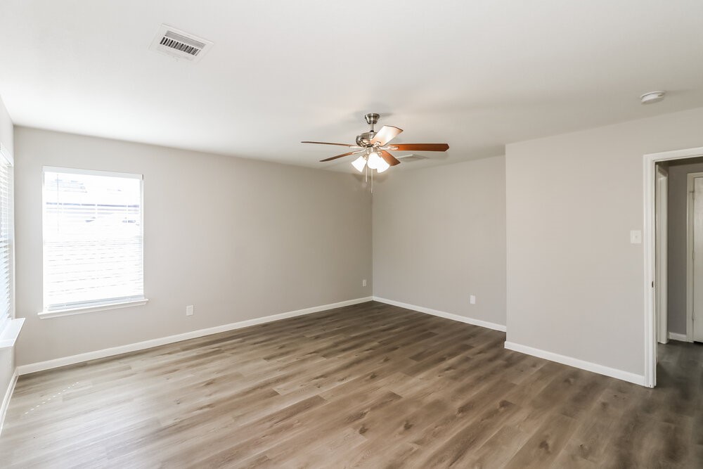 20622 Bishops Gate Lane Humble, TX 77338 - Photo 11 of 17 an empty room with wooden floor chandelier fan and windows