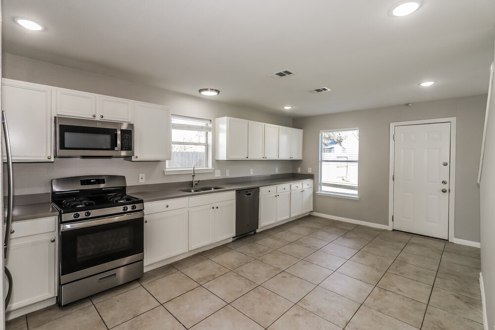 20622 Bishops Gate Lane Humble, TX 77338 - Photo 8 of 17 a large kitchen with a stove a sink dishwasher and a microwave oven on the blue kitchen countertops