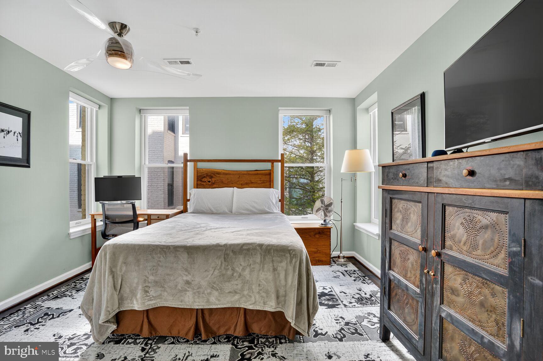 2627 Adams Mill Road Northwest, Unit 403 Washington, DC 20009 - Photo 17 of 38 a bedroom with a large bed and a flat tv screen on dresser