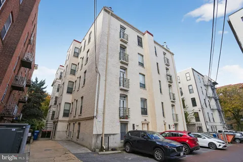 a bench sitting next to a white wall
