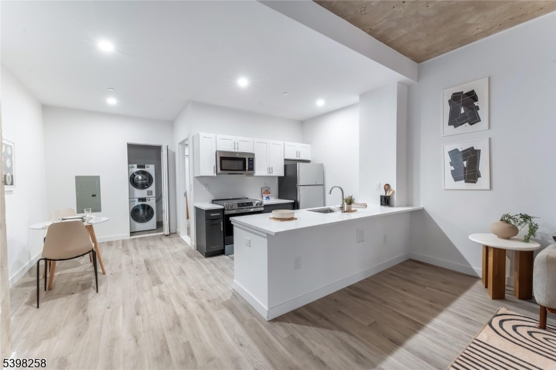 a kitchen with stainless steel appliances a stove top oven a sink dishwasher and white cabinets with wooden floor
