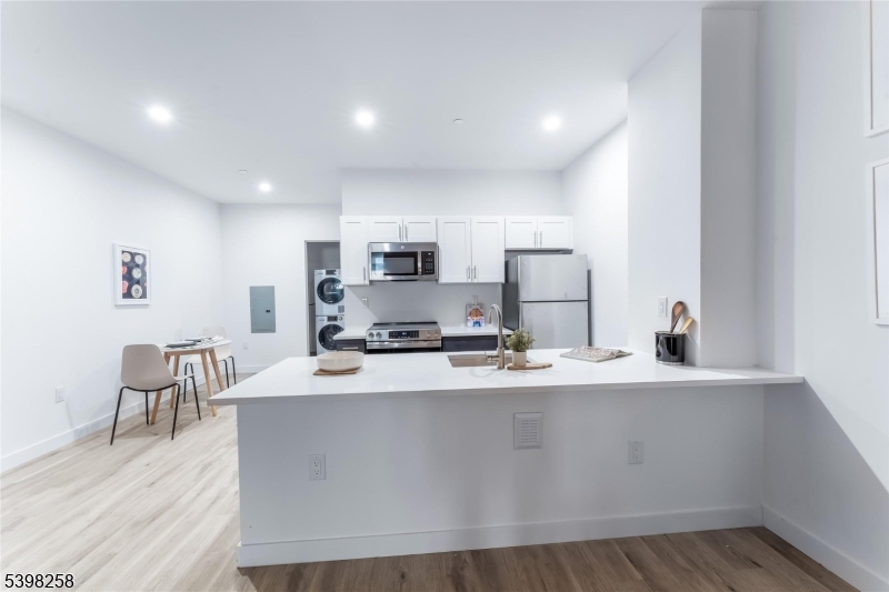 10 Commerce Court, Unit 7E Newark, NJ 07102 - Photo 2 of 18 a kitchen with stainless steel appliances a sink a stove a refrigerator with white cabinets and wooden floor