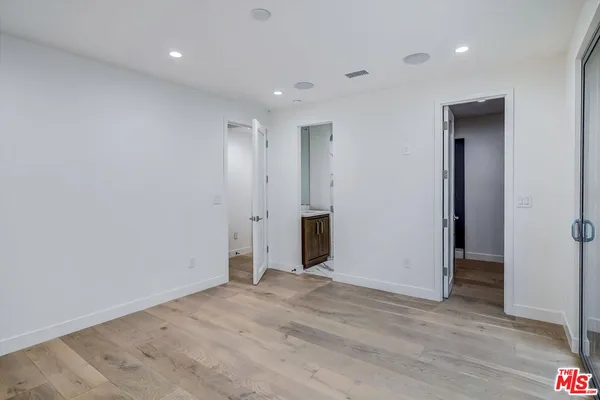 an empty room with wooden floor & windows