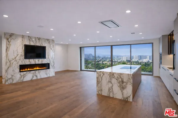 a view of kitchen living room with granite countertop a flat screen tv and a floor to ceiling window
