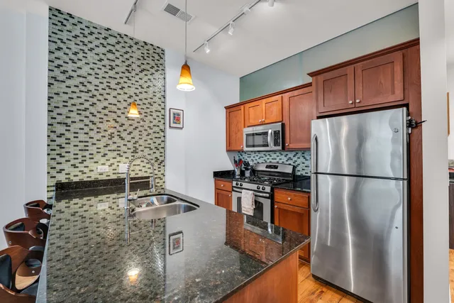 a kitchen with stainless steel appliances granite countertop a refrigerator a stove and a sink