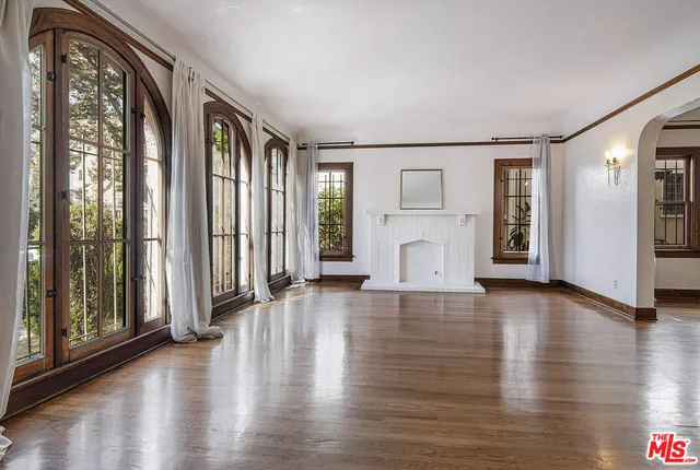 a view of an empty room with window and wooden floor