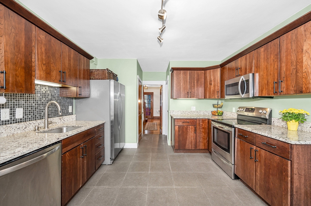 567 Andover Street, Unit A Lowell, MA 01852 - Photo 15 of 35 a kitchen with stainless steel appliances granite countertop a stove top oven a sink dishwasher and a refrigerator with wooden cabinets