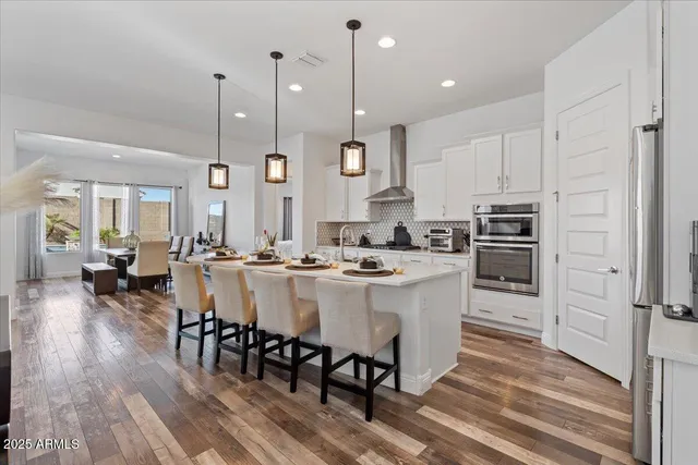a kitchen with a stove a kitchen island white cabinetry and couches with wooden floor