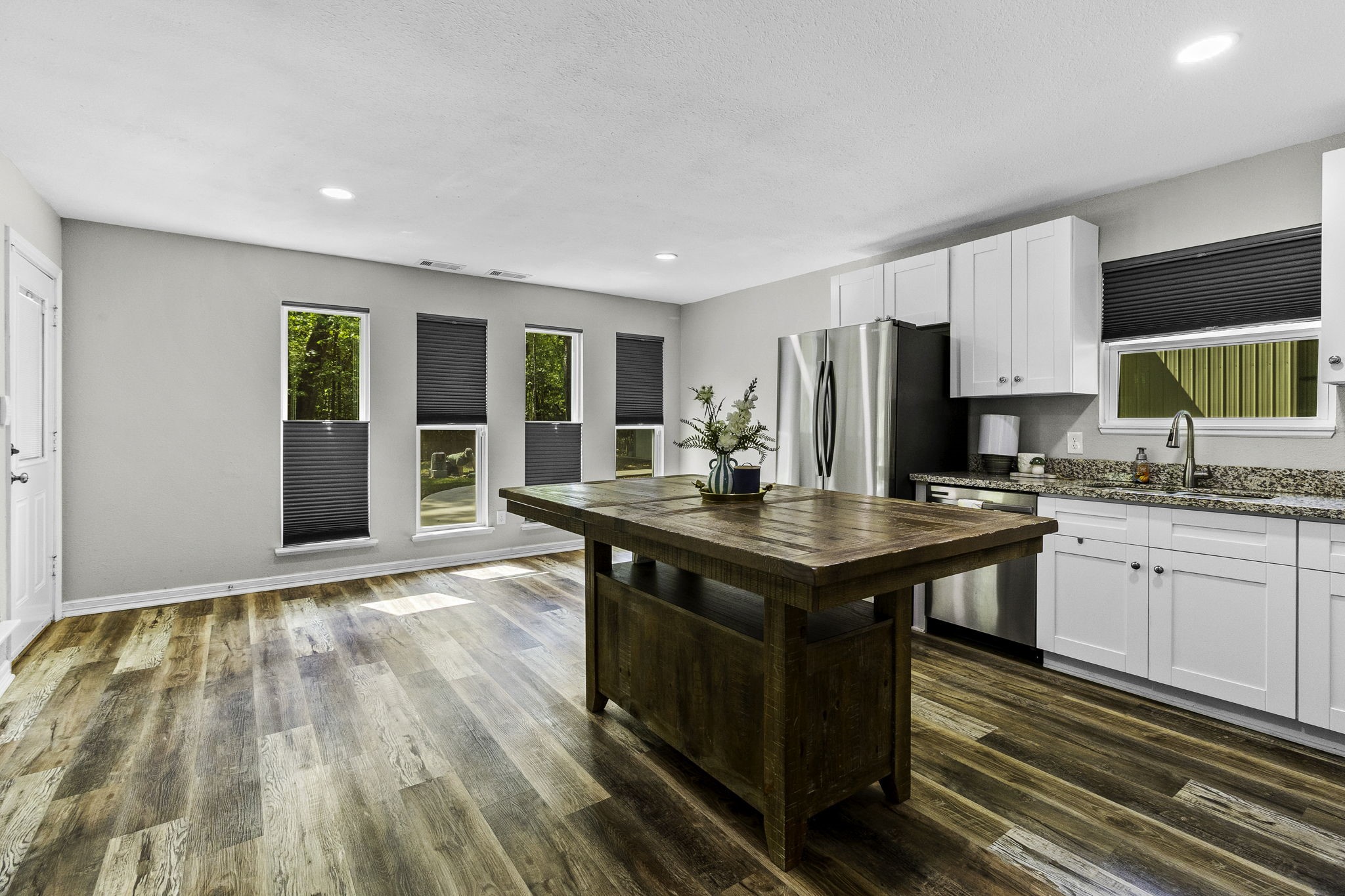21 Red Oak Circle Point Blank, TX 77364 - Photo 5 of 32 This photo showcases a modern kitchen with a spacious layout, featuring a large wooden island, stainless steel appliances, and sleek white cabinetry. The room is well-lit with natural light from multiple windows and has stylish wood flooring.