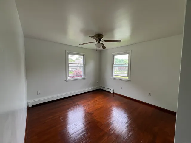 an empty room with wooden floor chandelier and windows