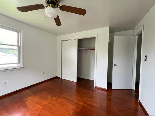 an empty room with wooden floor chandelier fan and windows