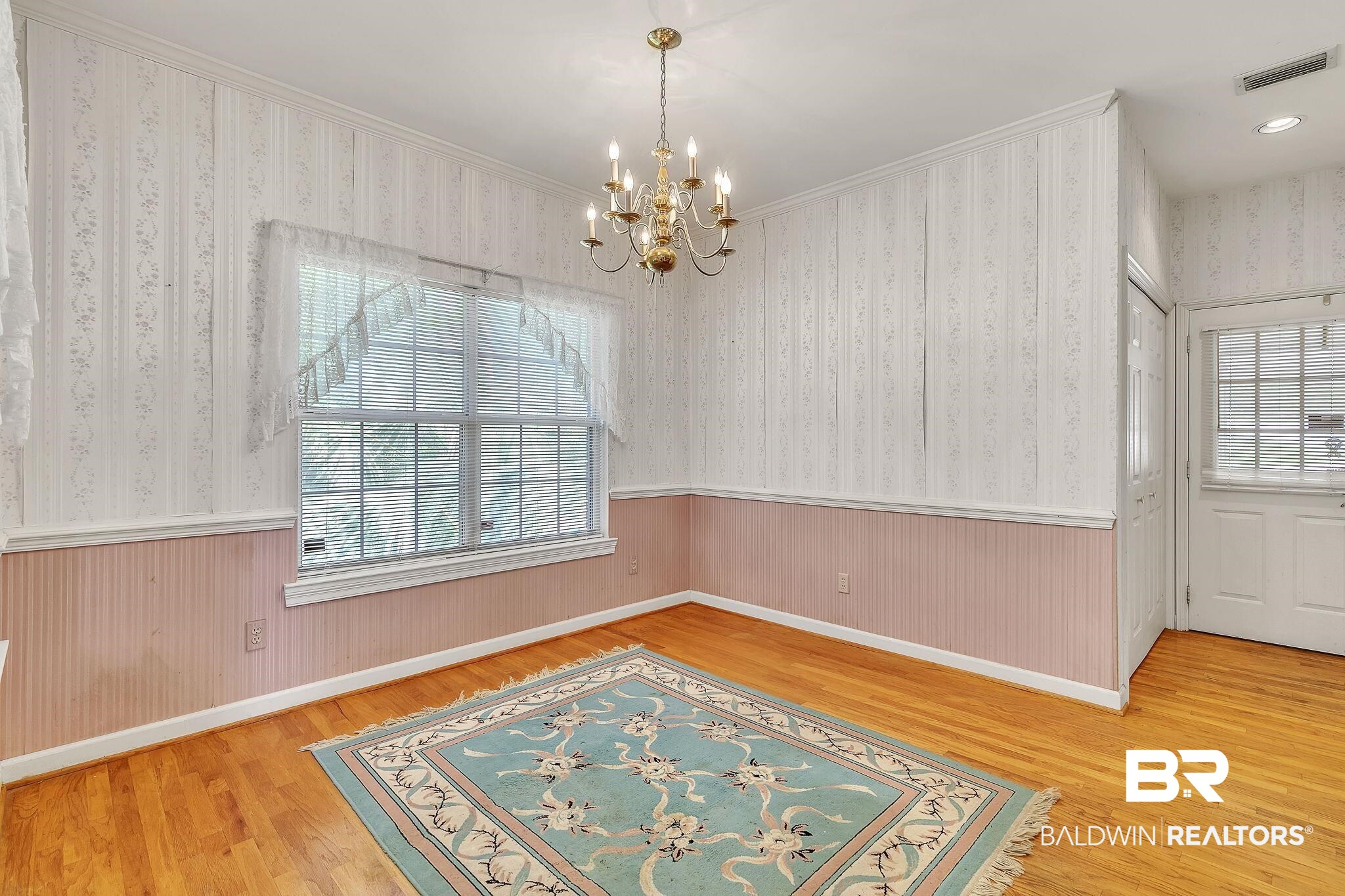 367 Ridgewood Drive Daphne, AL 36526 - Photo 26 of 71 Unfurnished dining area with a wainscoted wall, wood finished floors, visible vents, wallpapered walls, and an inviting chandelier