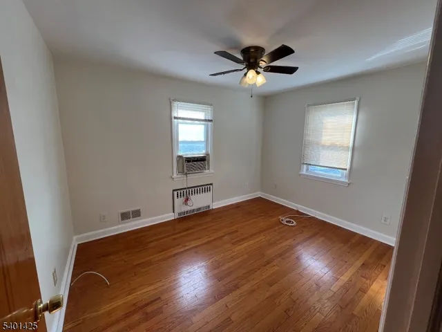 a view of an empty room with a window and wooden floor