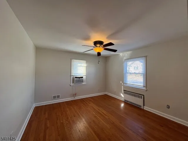 a view of empty room with wooden floor and fan