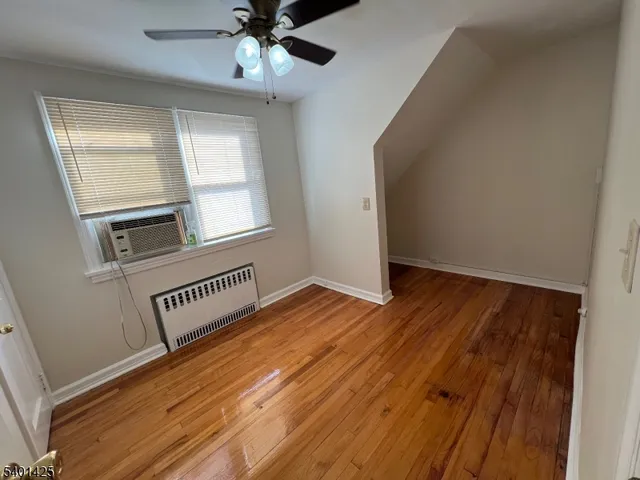 an empty room with wooden floor cabinet and windows